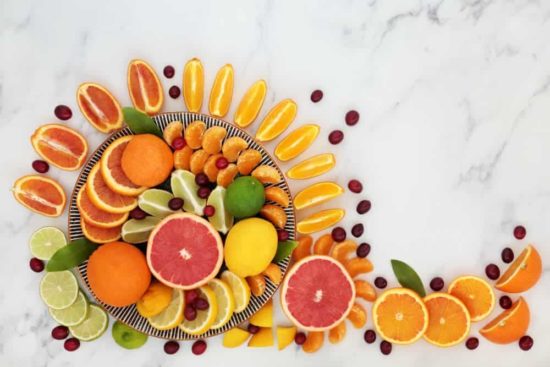 Healthy summer sunshine fruit with oranges, lemons, limes, grapefruit & cranberries high in antioxidants, anthocyanins, lycopene, fibre & vitamin c. Immune boosting health care concept. On marble.